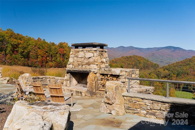 view of patio / terrace with a mountain view and an outdoor stone fireplace