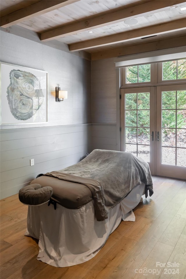 bedroom featuring light hardwood / wood-style flooring, beam ceiling, multiple windows, and access to exterior