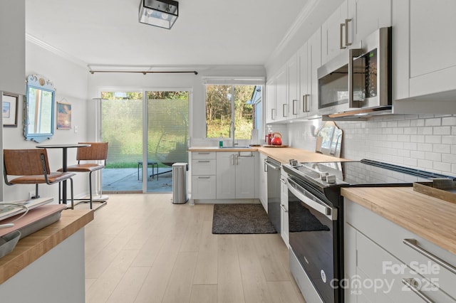 kitchen with white cabinets, wood counters, decorative backsplash, and appliances with stainless steel finishes