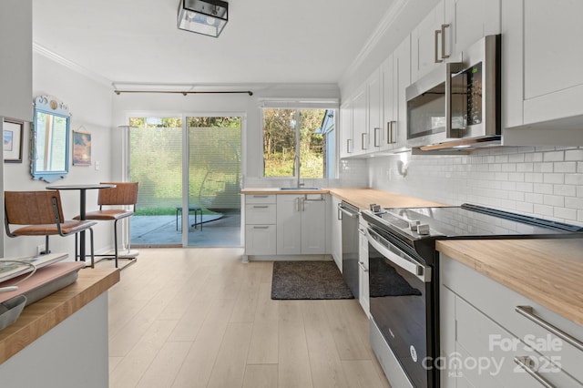 kitchen featuring white cabinets, stainless steel appliances, and wooden counters