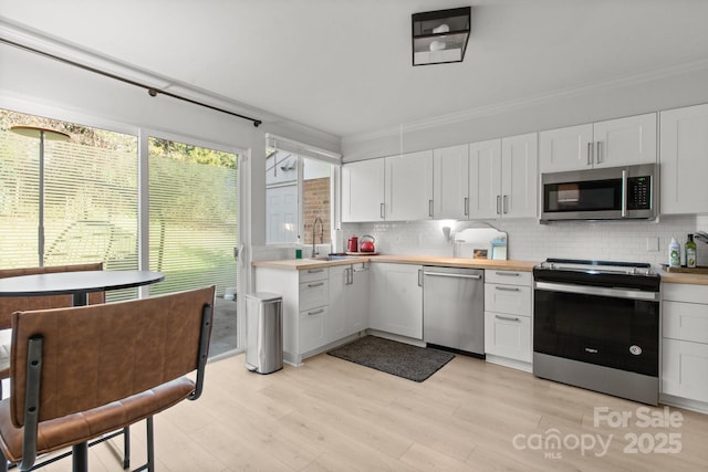 kitchen with sink, white cabinets, tasteful backsplash, and stainless steel appliances