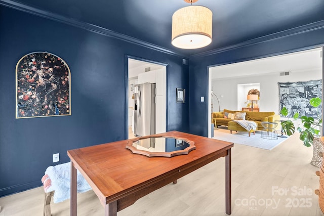 dining area featuring ornamental molding and light hardwood / wood-style floors