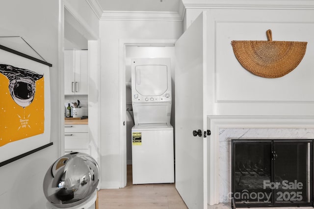 laundry area featuring light hardwood / wood-style floors, ornamental molding, and stacked washer and dryer