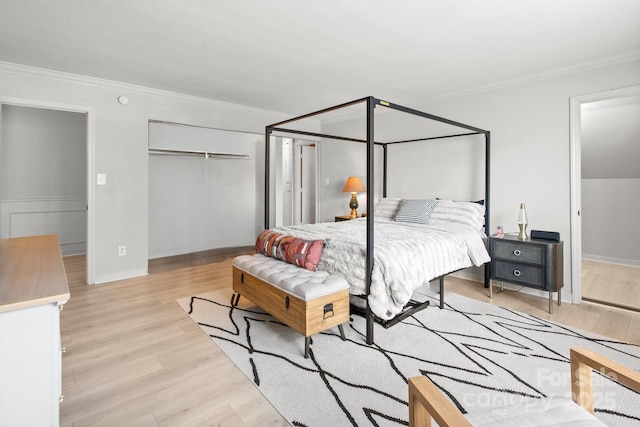 bedroom featuring light wood-type flooring, ornamental molding, and a closet