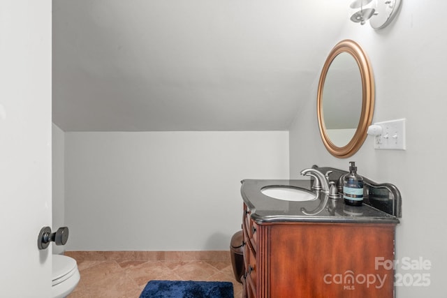 bathroom featuring vanity, toilet, vaulted ceiling, and tile patterned flooring