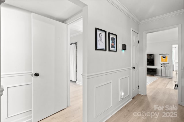 corridor with light hardwood / wood-style flooring and ornamental molding