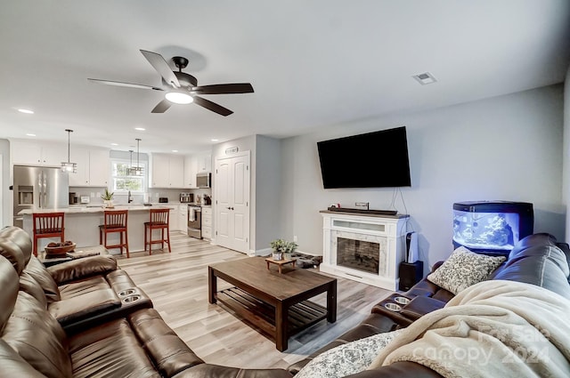 living room with light hardwood / wood-style flooring and ceiling fan