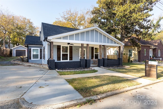 view of front of home with an outbuilding, a garage, a front lawn, a porch, and ceiling fan