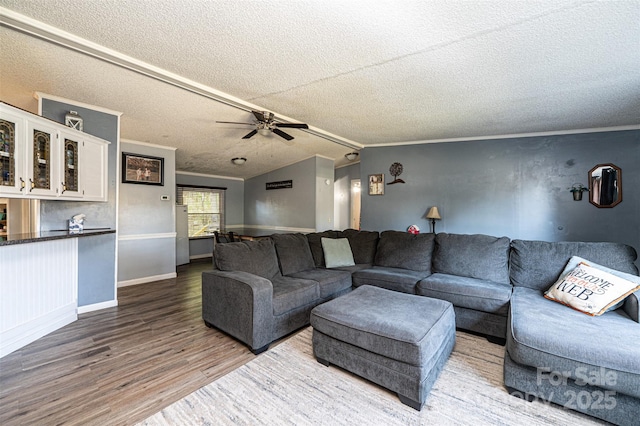 living room with hardwood / wood-style floors, ceiling fan, lofted ceiling, a textured ceiling, and crown molding