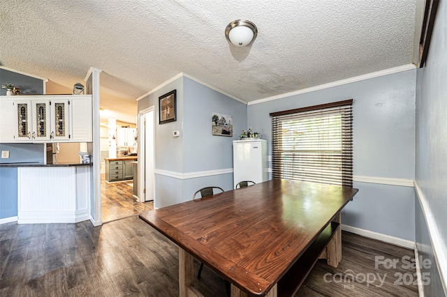 dining space with a textured ceiling, hardwood / wood-style floors, ornamental molding, and vaulted ceiling