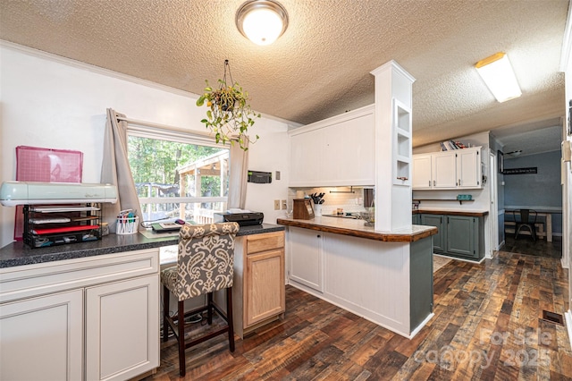 kitchen featuring a textured ceiling, white cabinets, a kitchen island, dark wood-type flooring, and a kitchen breakfast bar