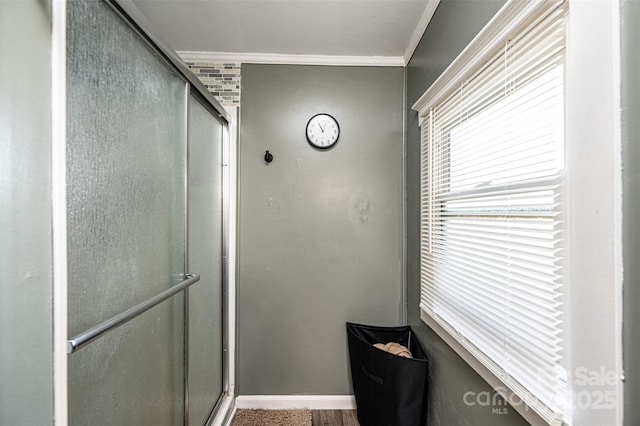 bathroom with a shower with shower door and crown molding