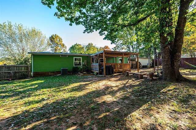 rear view of house with a deck, a yard, and central AC