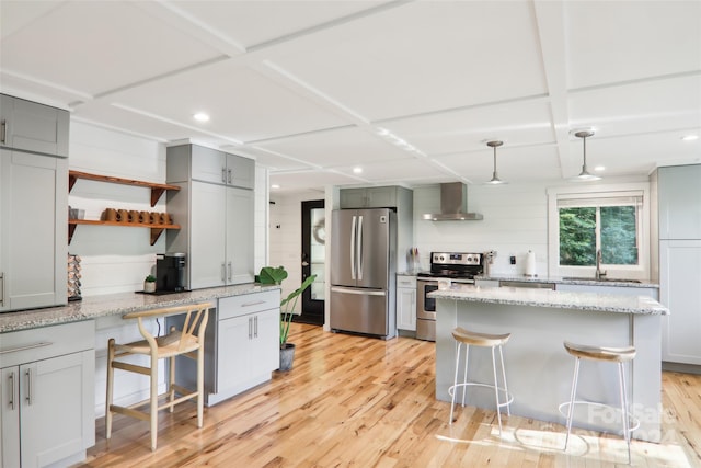 kitchen featuring wall chimney exhaust hood, a breakfast bar, stainless steel appliances, and light hardwood / wood-style floors