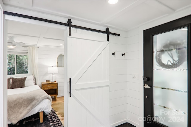 interior space with a barn door, hardwood / wood-style flooring, and wood walls