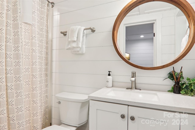 bathroom featuring wood walls, vanity, toilet, and walk in shower