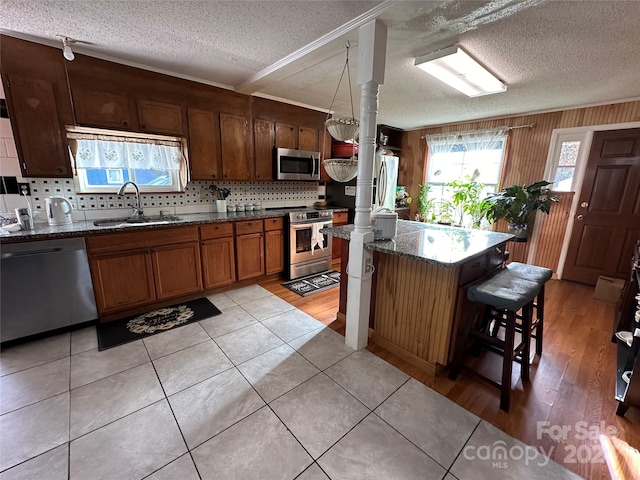 kitchen featuring appliances with stainless steel finishes, sink, backsplash, a textured ceiling, and a kitchen breakfast bar