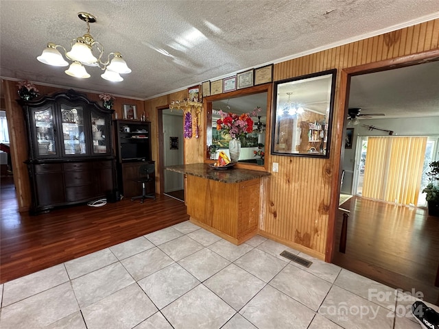 kitchen with ceiling fan with notable chandelier, a textured ceiling, decorative light fixtures, ornamental molding, and light hardwood / wood-style flooring