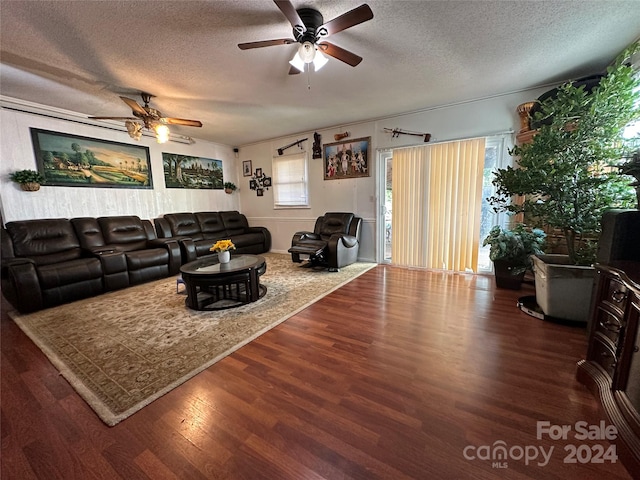 living room with a textured ceiling, dark wood-type flooring, and ceiling fan