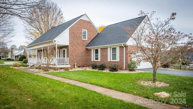 view of front of house featuring a garage, covered porch, and a front lawn