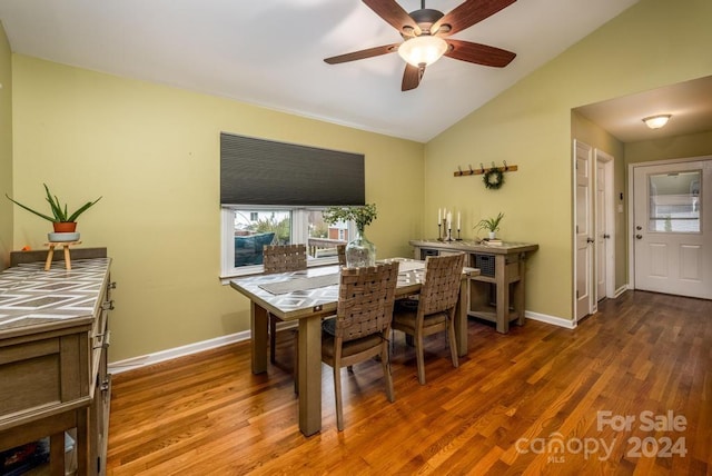 dining space with ceiling fan, vaulted ceiling, and hardwood / wood-style flooring