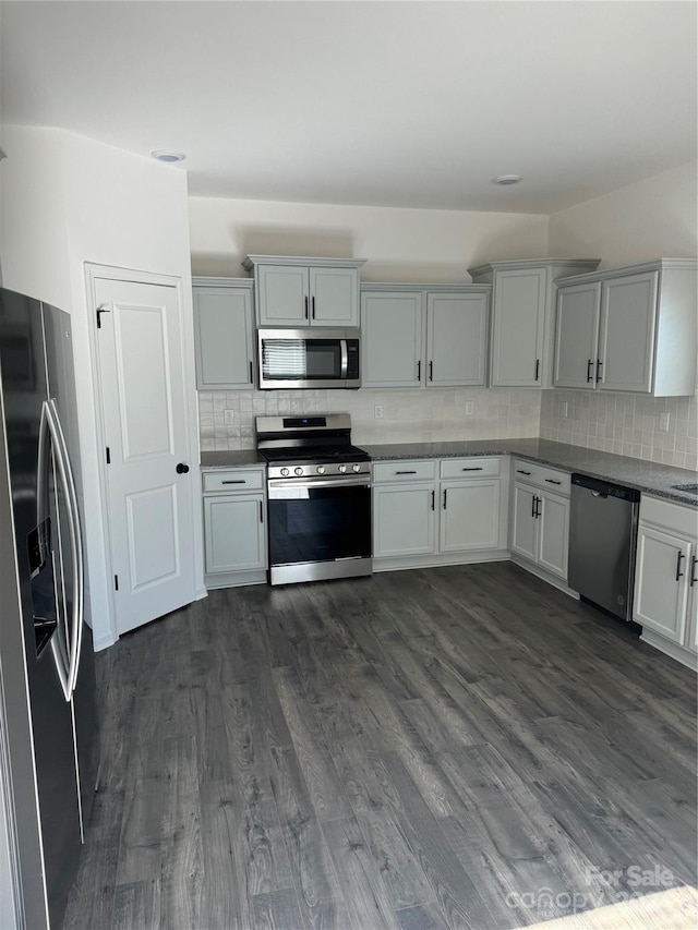 kitchen featuring appliances with stainless steel finishes, decorative backsplash, and dark hardwood / wood-style floors