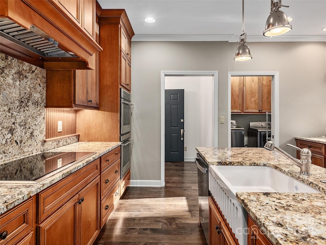 kitchen with ornamental molding, dark hardwood / wood-style floors, stainless steel appliances, washing machine and dryer, and decorative light fixtures