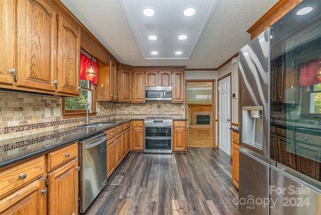 kitchen with appliances with stainless steel finishes, sink, crown molding, decorative backsplash, and dark hardwood / wood-style floors