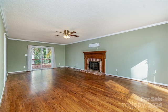 unfurnished living room with wood-type flooring, a textured ceiling, a brick fireplace, ceiling fan, and crown molding