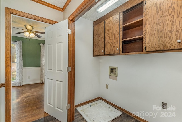 washroom featuring electric dryer hookup, dark hardwood / wood-style floors, ornamental molding, cabinets, and a textured ceiling