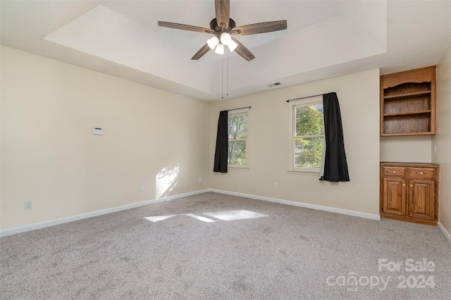 carpeted spare room featuring ceiling fan and a tray ceiling