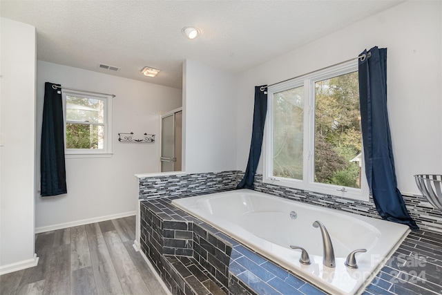 bathroom with hardwood / wood-style flooring, a textured ceiling, and plenty of natural light