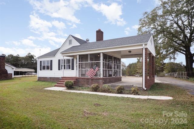 back of house featuring a sunroom, a lawn, and a carport