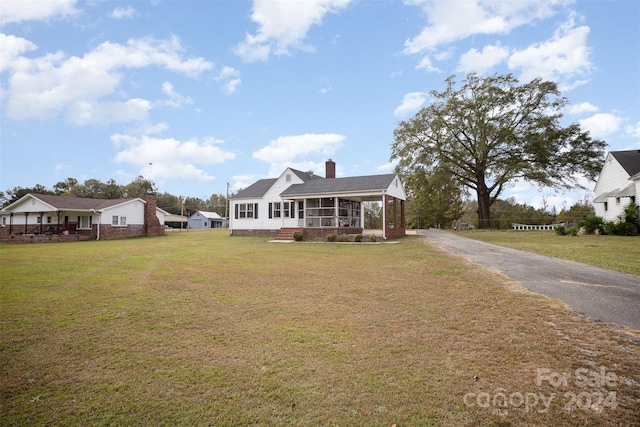 view of front of house with a front yard and a sunroom