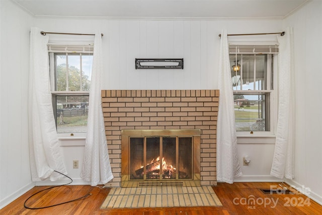 interior details with a brick fireplace, hardwood / wood-style floors, and crown molding