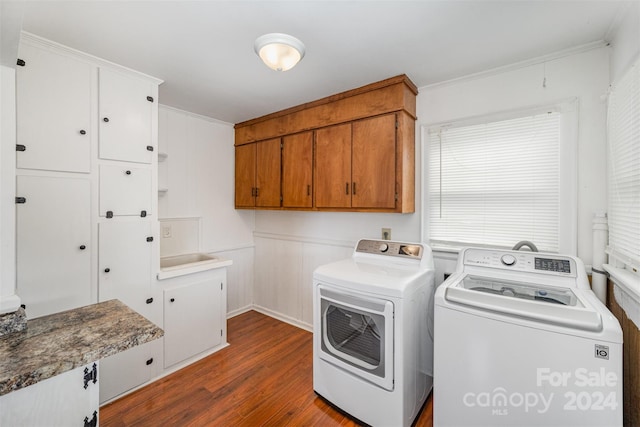 clothes washing area with cabinets, washer and dryer, dark wood-type flooring, and ornamental molding