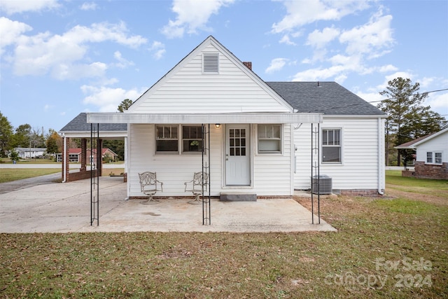 view of front of house featuring a front lawn, central air condition unit, and a carport