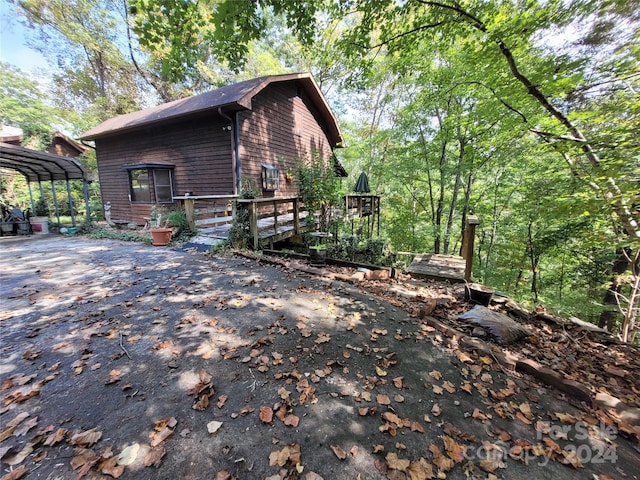 view of property exterior featuring a wooden deck and a carport