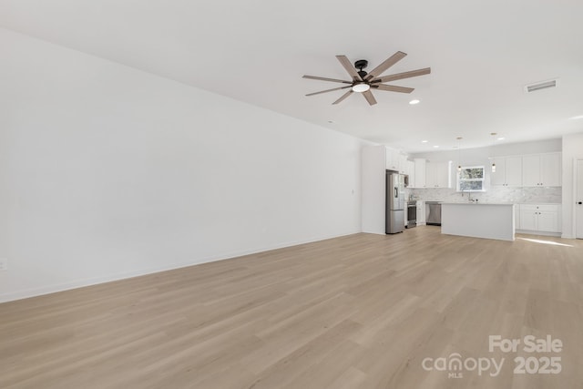 unfurnished living room with ceiling fan and light hardwood / wood-style floors