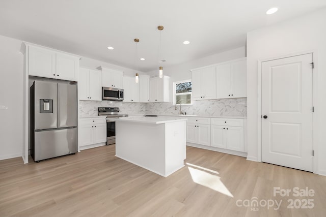 kitchen featuring decorative light fixtures, white cabinets, and appliances with stainless steel finishes