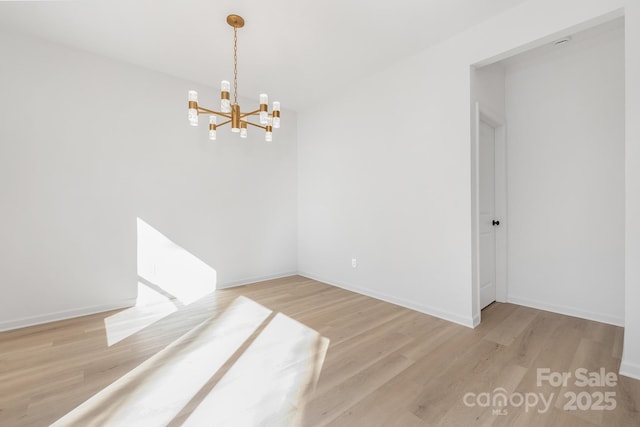 unfurnished room featuring light hardwood / wood-style flooring and a notable chandelier