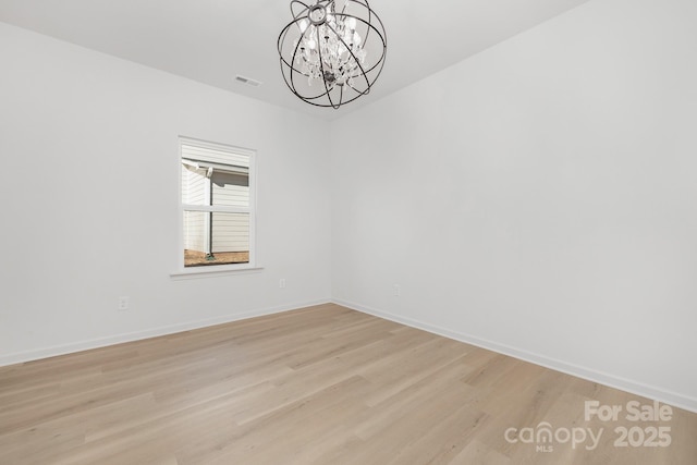 empty room with light hardwood / wood-style flooring and a chandelier