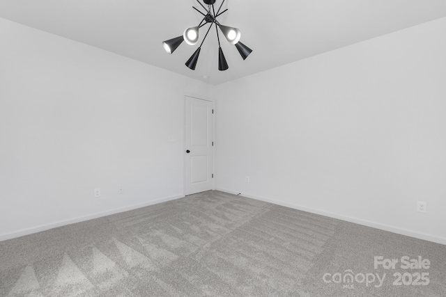 carpeted spare room with a chandelier