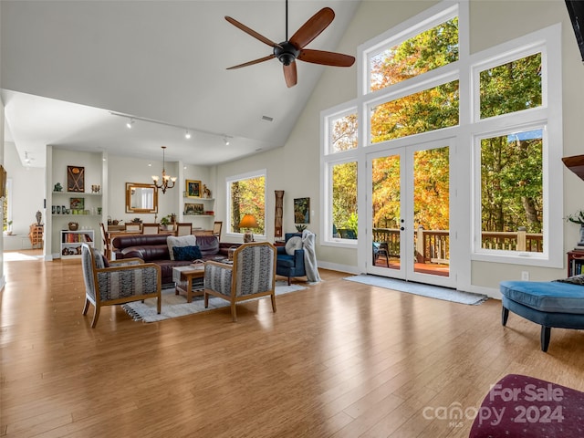 living room featuring track lighting, high vaulted ceiling, ceiling fan with notable chandelier, and light wood-type flooring