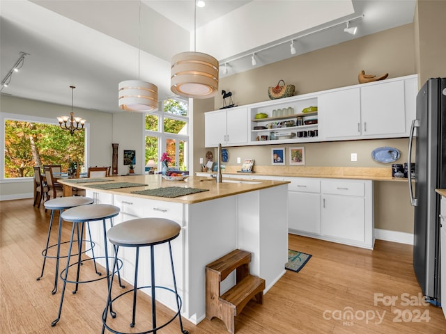 kitchen with a center island with sink, light hardwood / wood-style floors, pendant lighting, and rail lighting