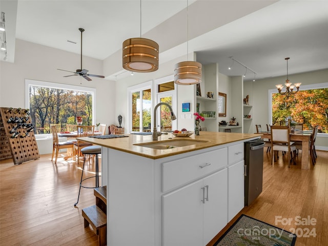 kitchen with a kitchen island with sink, light hardwood / wood-style flooring, sink, pendant lighting, and white cabinets