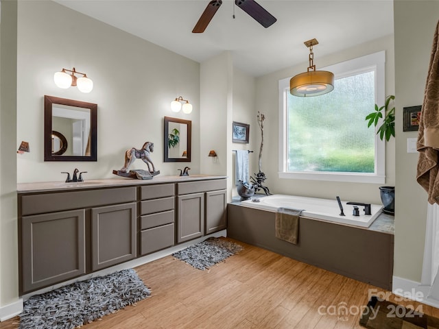 bathroom featuring vanity, a tub, hardwood / wood-style flooring, and ceiling fan