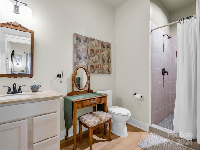 bathroom with vanity, curtained shower, hardwood / wood-style flooring, and toilet