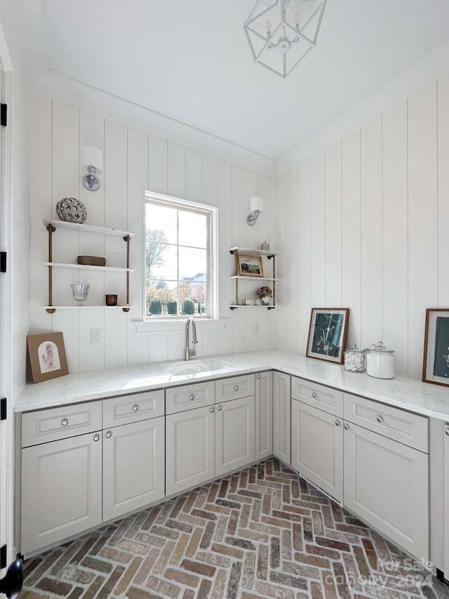 kitchen featuring gray cabinetry, sink, and wooden walls