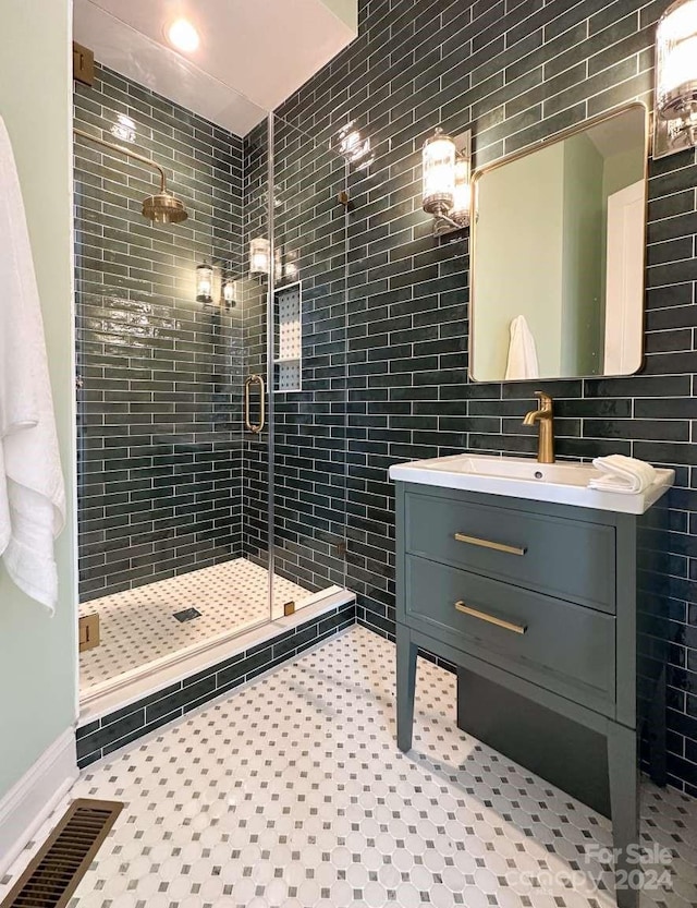 bathroom with vanity, tile patterned floors, decorative backsplash, and a shower with door